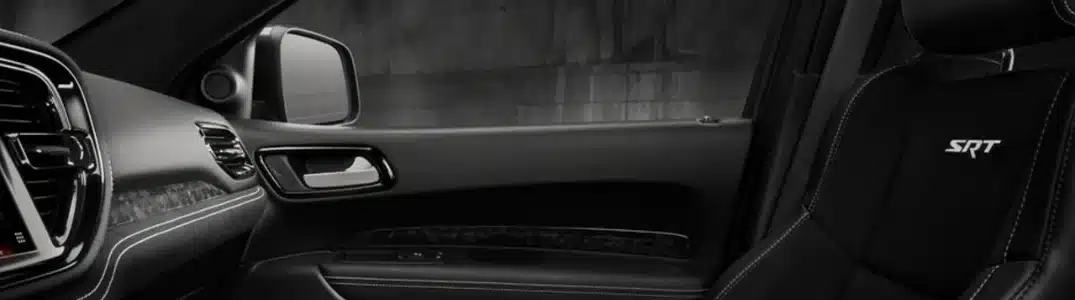 Black car interior with SRT-embroidered seat, sleek dashboard, and door panel design.