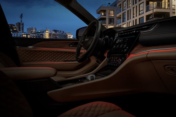 Luxury car interior at night, featuring leather seats, ambient lighting, and a sleek dashboard against a city backdrop.