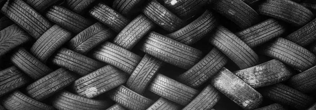 Enchevêtrement de pneus usés disposés en motif entrecroisé, illustrant le recyclage.