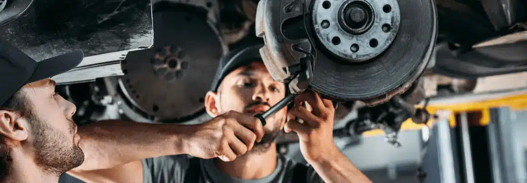 Mechanic tightening bolts on a car brake disc in an auto repair shop.