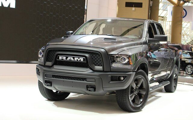 Camionnette RAM gris foncé exposée à l'intérieur avec un design moderne et des roues noires.
