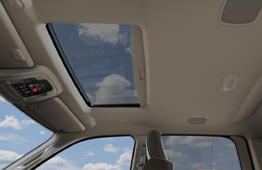 Car interior with panoramic sunroof, showing blue sky and clouds, enhancing natural light.