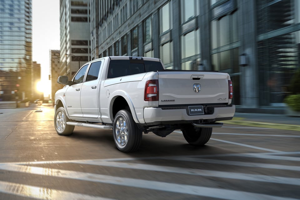 Camionnette Ram Laramie blanche roulant en ville au coucher du soleil.