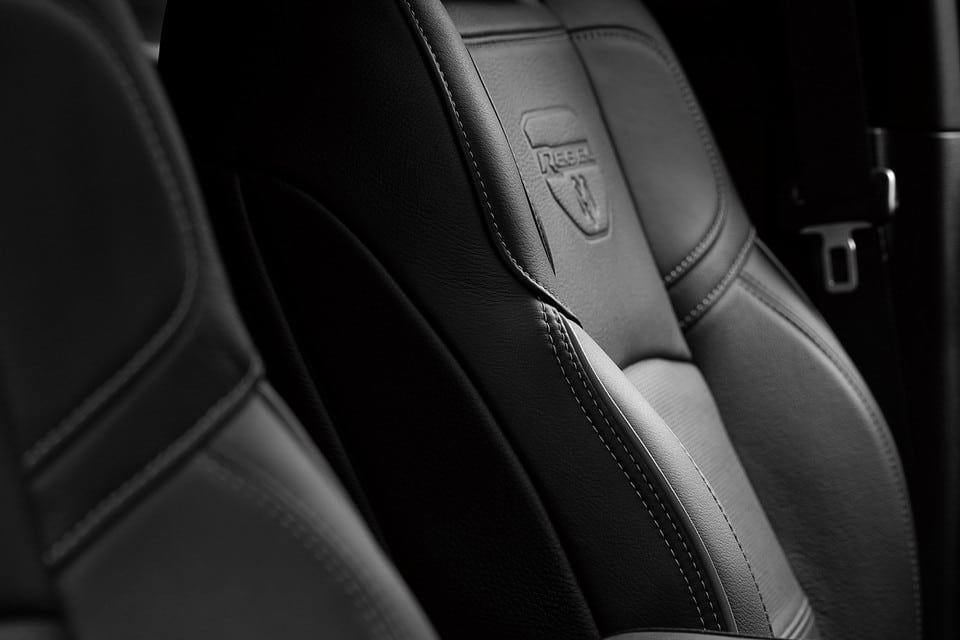 Close-up of a black leather car seat with “Rebel” logo, showcasing detailed stitching.