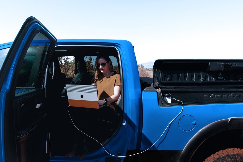 Personne utilisant un ordinateur portable dans une camionnette bleue, porte ouverte.
