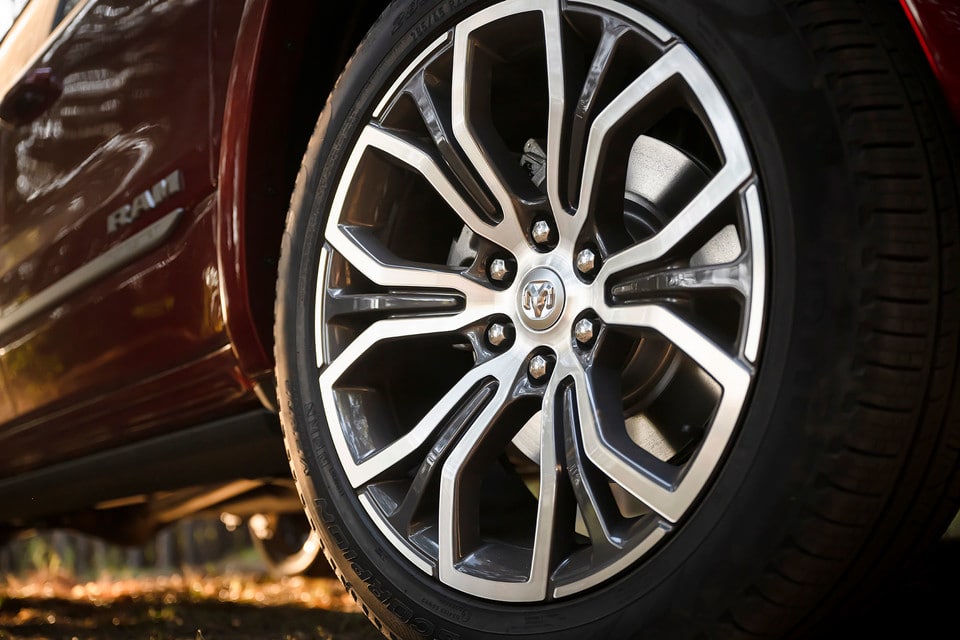 Close-up of a polished alloy wheel on a red pickup truck, highlighting the design and detailed emblem.