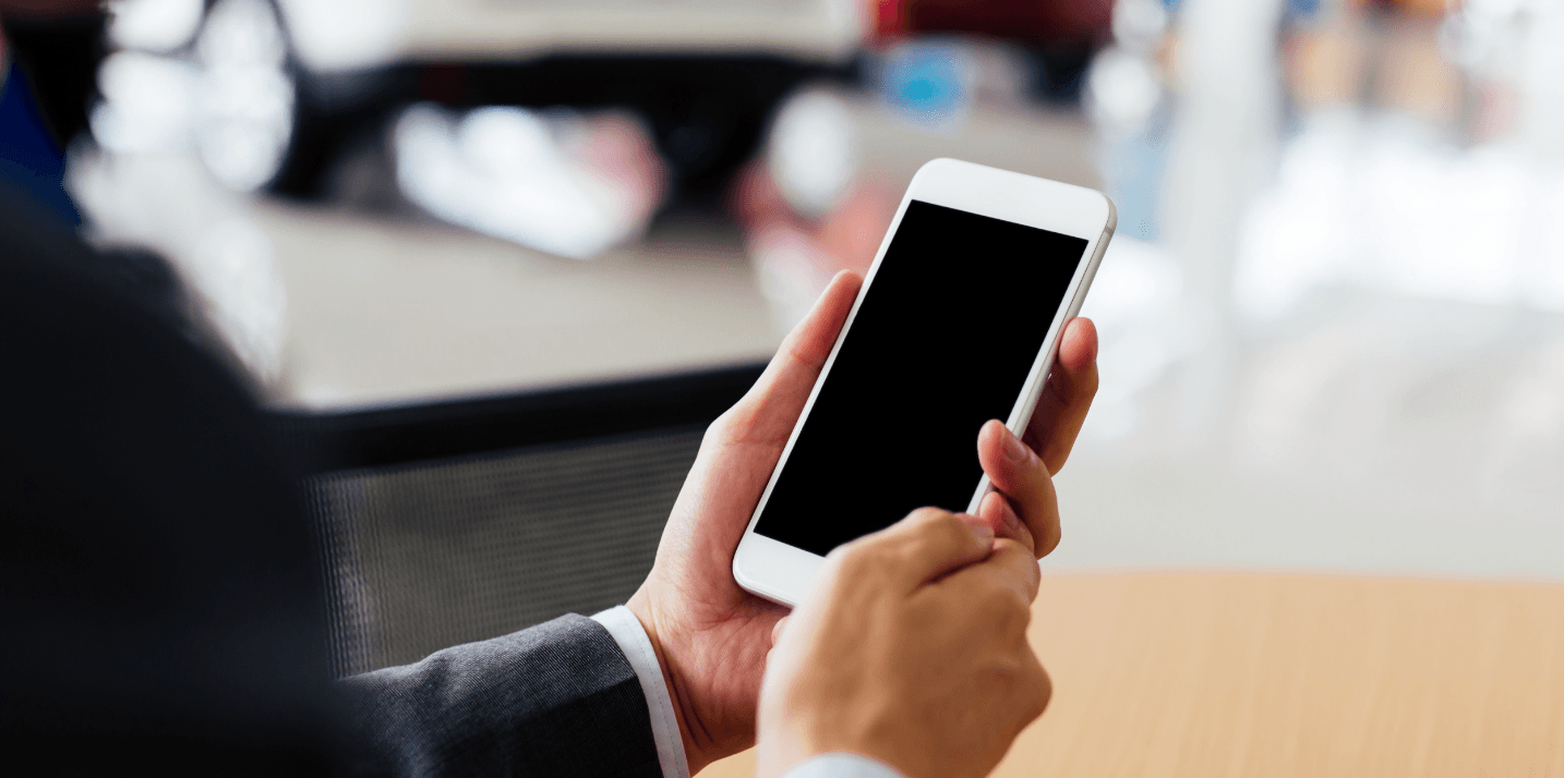 Personne tenant un téléphone intelligent, en gros plan sur l'écran vide, dans un contexte professionnel.