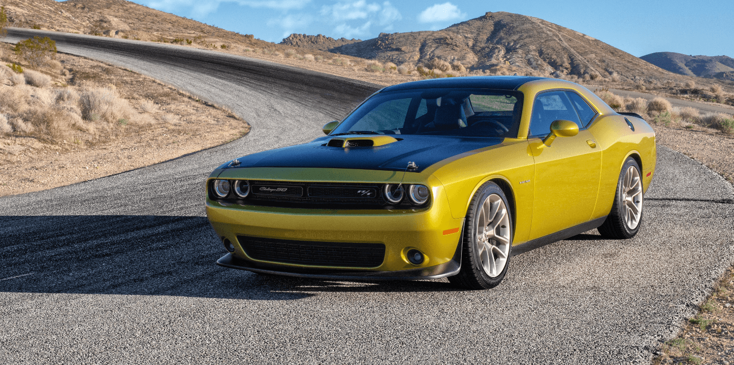 Voiture sport jaune sur une route sinueuse du désert sous un ciel bleu, mettant en valeur son design élégant.