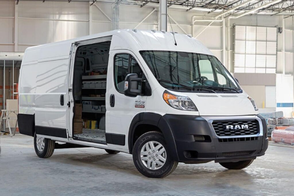 Fourgon RAM ProMaster blanc avec portes ouvertes, stationné à l'intérieur d'un entrepôt moderne.