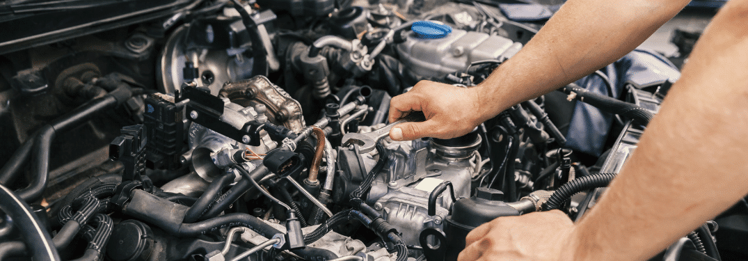 Mécanicien inspectant le moteur d'une voiture, concentré sur les tâches de réparation et d'entretien.