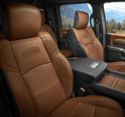 Luxurious brown leather truck interior with embossed seats and scenic mountain view through windows.