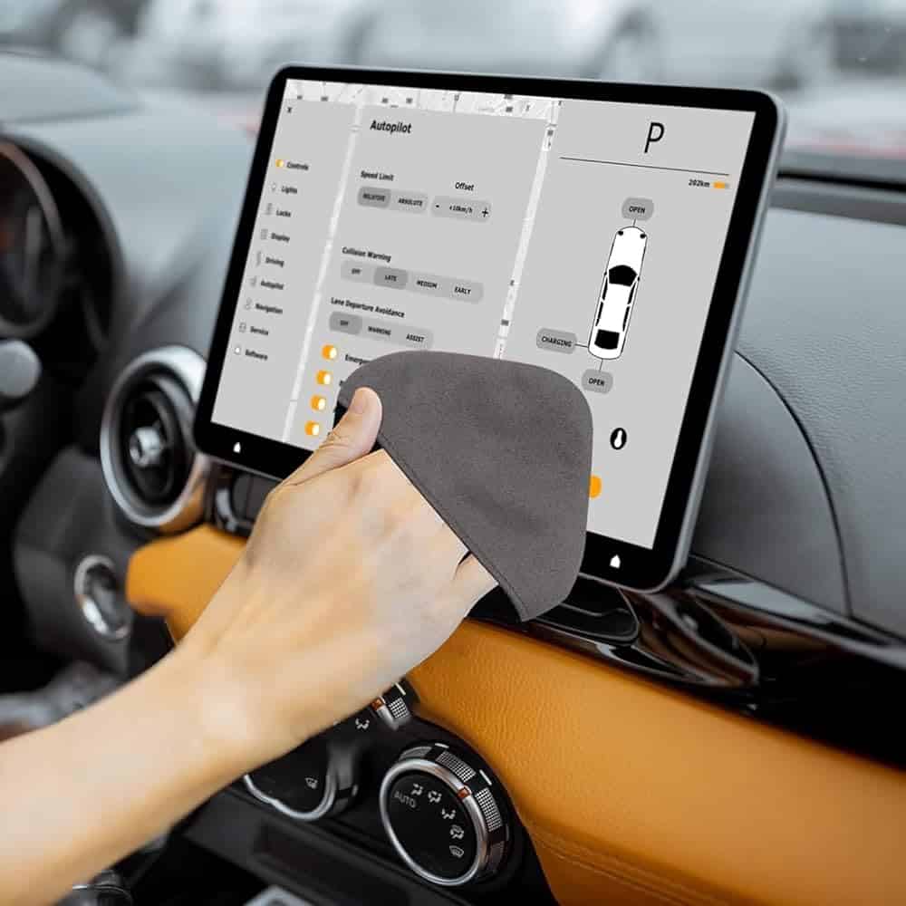 Nettoyage de l'écran d'infodivertissement d'une voiture affichant les commandes du pilote automatique et la navigation.